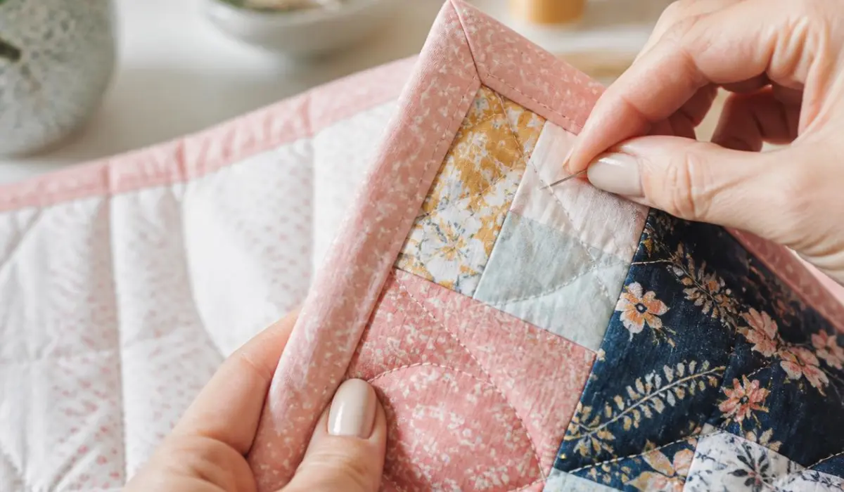 Sewing quilt binding onto a colorful patchwork quilt
