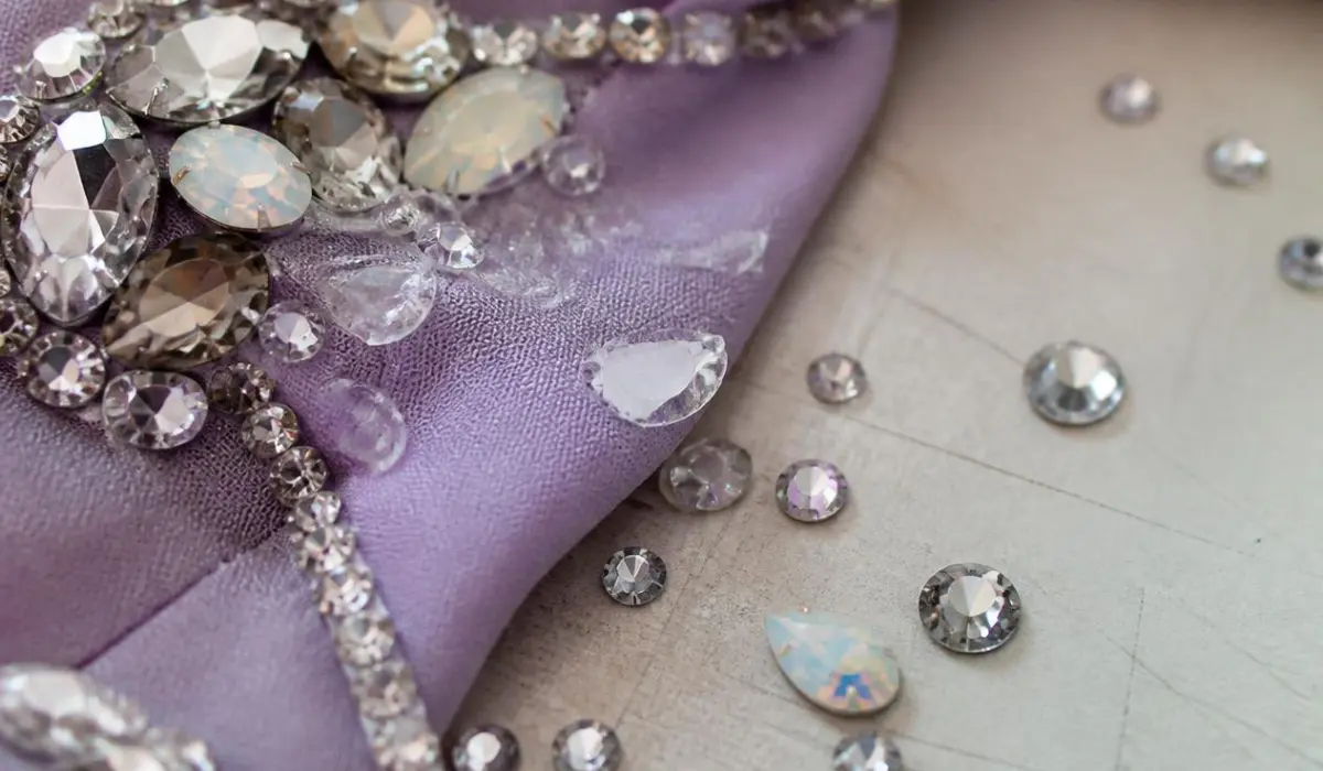 A detailed macro shot shows rhinestone appliqué lifting off fabric