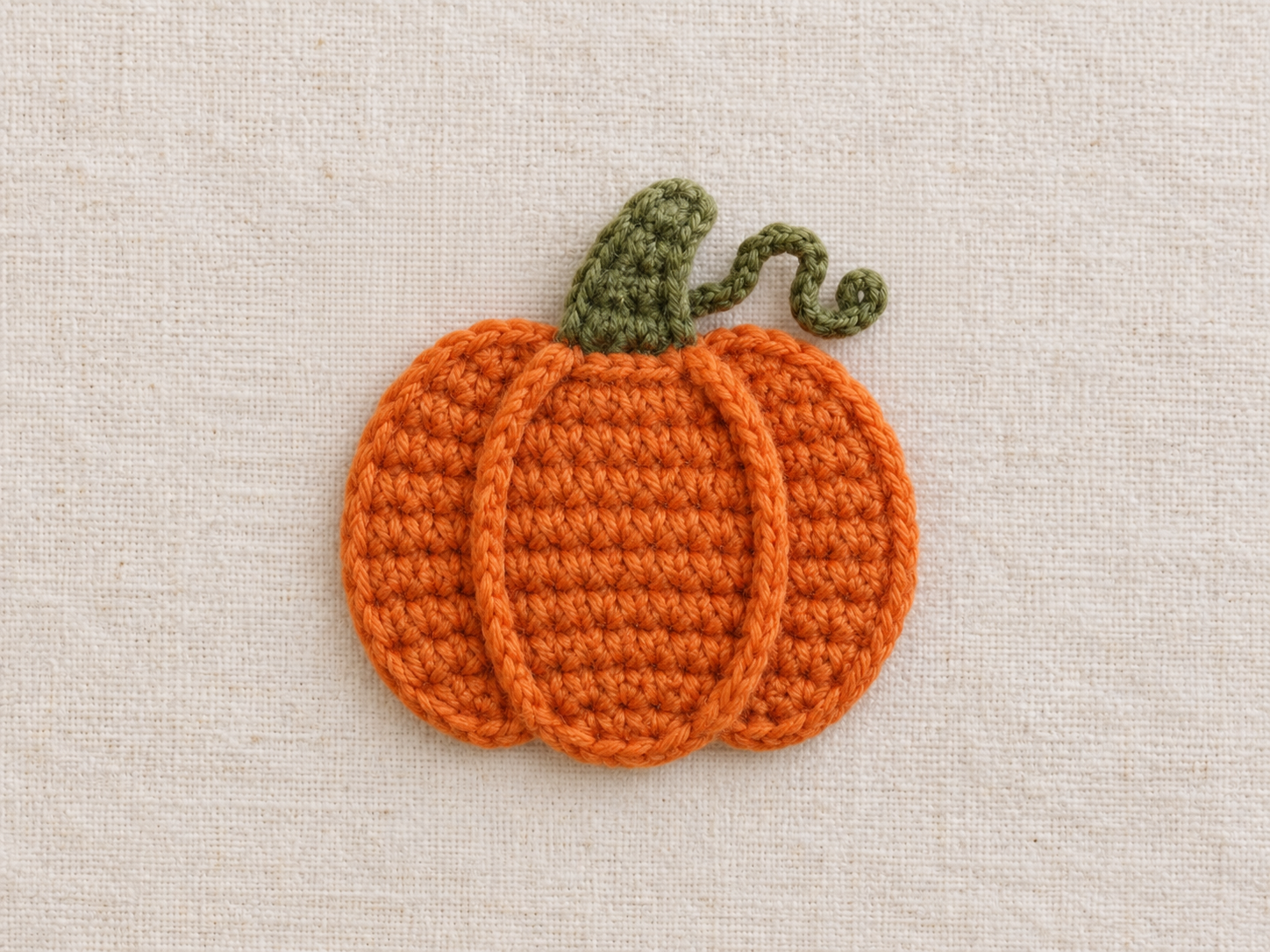 Orange crochet pumpkin appliqué with green stem and curled tendril